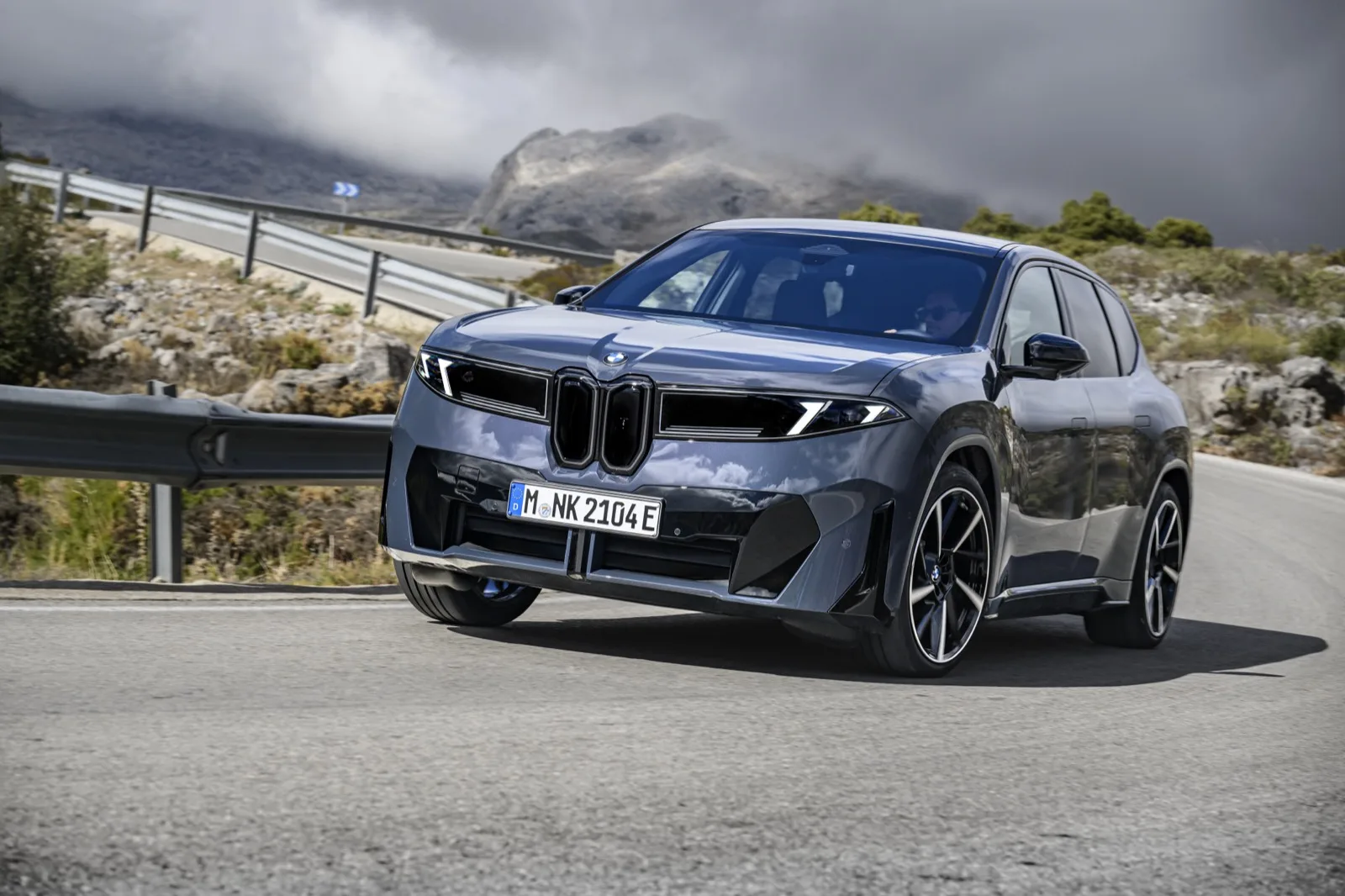 BMW iX3 in donkergrijs dynamisch op bergweg